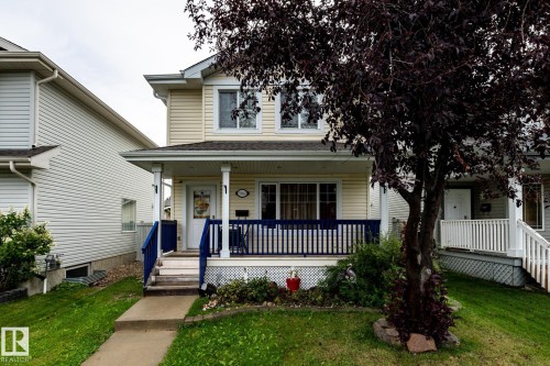 Light-colored siding exterior with a front porch featuring blue railing and white pillars - 5907 203 Street Nw, Edmonton, AB 