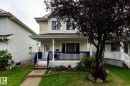 Light-colored siding exterior with a front porch featuring blue railing and white pillars - 5907 203 Street Nw, Edmonton, AB 