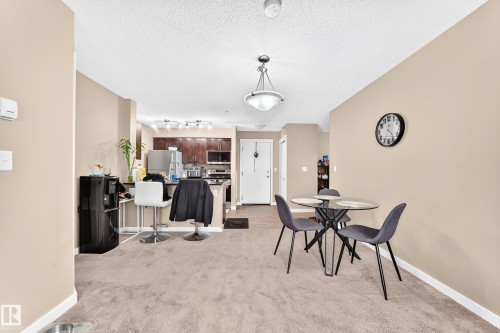 Kitchen featuring wood-finish cabinetry, stainless steel appliances, and a breakfast bar - #306 5370 Chappelle Rd Sw, Edmonton, AB 