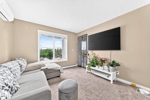 Neutral-toned walls, carpet flooring, a window with a white frame, and a door with a screen - #306 5370 Chappelle Rd Sw, Edmonton, AB 