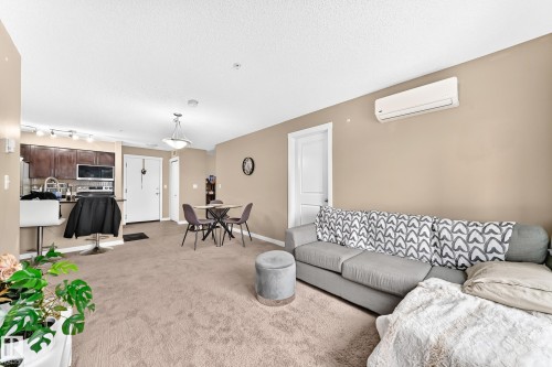 Open-concept living area with carpet flooring, a mini-split air conditioning unit, and recessed lighting - #306 5370 Chappelle Rd Sw, Edmonton, AB 
