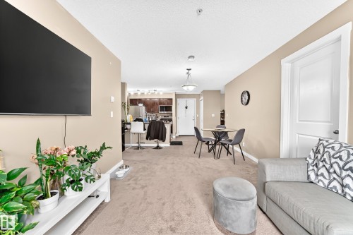 Neutral tone wall paint, carpeted flooring, white interior doors, pendant lighting, and recessed lighting - #306 5370 Chappelle Rd Sw, Edmonton, AB 