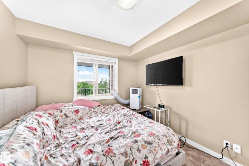 Recessed ceiling detail, neutral wall paint, window with white trim, wall-mounted television, and carpeted flooring - #306 5370 Chappelle Rd Sw, Edmonton, AB 