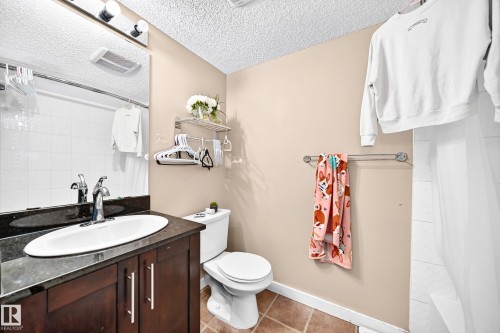 Vanity with dark wood-finish cabinetry, white oval undermount sink, and polished chrome faucet - #306 5370 Chappelle Rd Sw, Edmonton, AB 