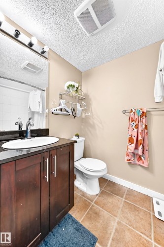 Dark wood-finish vanity with a dark countertop and undermount sink - #306 5370 Chappelle Rd Sw, Edmonton, AB 