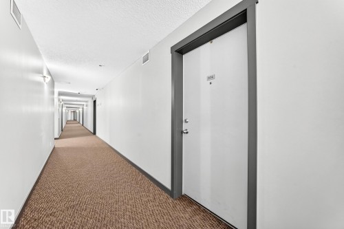 Entry door with a dark trim, light-colored walls, and textured carpet flooring - #306 5370 Chappelle Rd Sw, Edmonton, AB 
