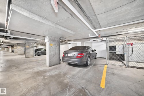 Concrete parking garage with marked spaces and overhead utility lines - #306 5370 Chappelle Rd Sw, Edmonton, AB 