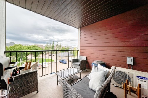 Outdoor balcony featuring a black metal railing and red wood-paneled siding - #306 5370 Chappelle Rd Sw, Edmonton, AB 