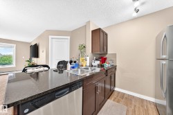 Kitchen featuring dark wood cabinetry, a double basin stainless steel sink, stainless steel dishwasher, and wood-finish flooring - 