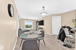Open-concept living area with carpet flooring, a large window, a ceiling-mounted light fixture, and a white paneled door - 
