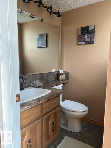 Vanity with integrated sink, wood-finish cabinetry, and dark countertop - 29 Lindbergh Crescent, St. Albert, AB 