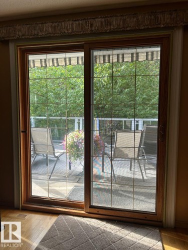 Wood-frame sliding glass door with grid panes, opening to an outdoor patio with a visible awning - 29 Lindbergh Crescent, St. Albert, AB 