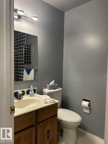 Wood-finish vanity with a built-in sink, wall-mounted mirror, and overhead chrome light fixture - 29 Lindbergh Crescent, St. Albert, AB 