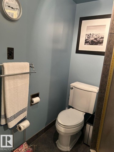 Powder room with a white toilet, blue wall paint, and dark tile flooring - 29 Lindbergh Crescent, St. Albert, AB 