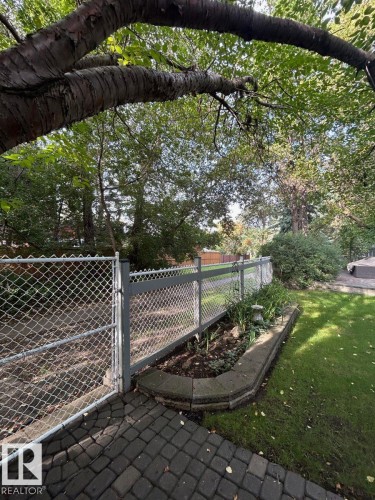 Paved patio leading to a chain-link fence with a privacy screen - 29 Lindbergh Crescent, St. Albert, AB 