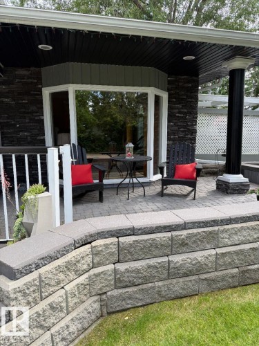 Bay window with white trim, dark stacked stone exterior, covered patio, paver patio surface, and a retaining wall - 29 Lindbergh Crescent, St. Albert, AB 