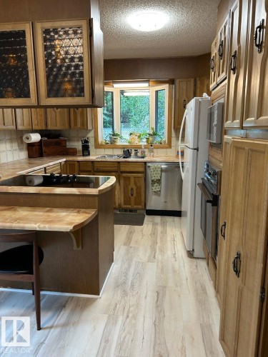 Light wood-finish flooring, built-in oven, bay window, light wood cabinetry, and a circular flush-mount ceiling light - 29 Lindbergh Crescent, St. Albert, AB 