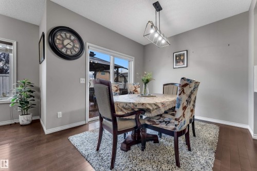 Hardwood-finish flooring, neutral wall paint, and a contemporary linear pendant light fixture - 3230 21A Avenue Nw, Edmonton, AB 