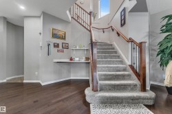 Carpeted staircase with wood-finish handrails and wrought iron balusters, wood-finish flooring, and a built-in wall shelf - 
