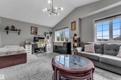 Vaulted ceiling, contemporary chandelier, multiple windows, built-in shelving, and carpeted flooring - 