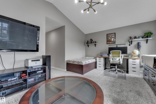 Vaulted ceiling with a contemporary chandelier, neutral wall tones, and plush carpeting throughout - 3230 21A Avenue Nw, Edmonton, AB 