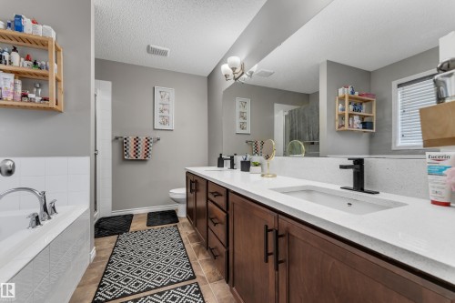 Double vanity with black hardware, white rectangular sinks, and an extended mirror - 3230 21A Avenue Nw, Edmonton, AB 