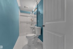 Tiled shower with glass enclosure, white subway tile surround, white pedestal sink, and white tile flooring - 