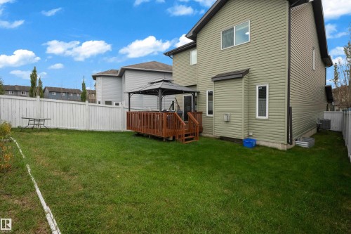 Expansive green space with a wooden deck, covered gazebo, white privacy fence, and vinyl siding exterior - 3230 21A Avenue Nw, Edmonton, AB 