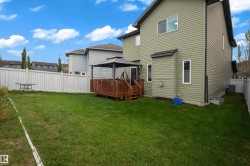 Expansive green space with a wooden deck, covered gazebo, white privacy fence, and vinyl siding exterior - 