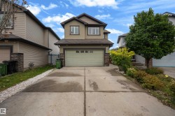 Two-story residence featuring a front-facing garage, stone veneer accents, and a concrete driveway - 