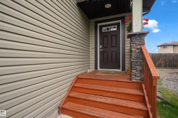 Entry featuring a four-panel door with decorative glass, wood steps, and a stacked stone column - 