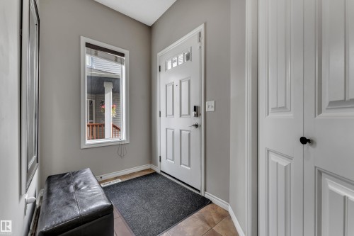 Entryway featuring a white paneled door with glass inserts, an adjacent window, and neutral wall tones - 3230 21A Avenue Nw, Edmonton, AB 