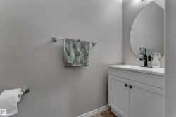 White vanity with matte black hardware, integrated rectangular sink, and a circular wall mirror - 