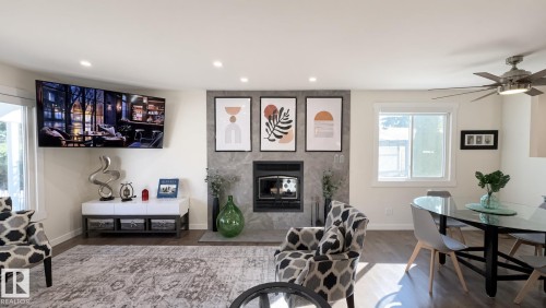 Recessed lighting, wood-finish flooring, stone-clad fireplace with hearth, built-in ceiling fan, and white trim windows - 3508 106A Street Nw, Edmonton, AB 