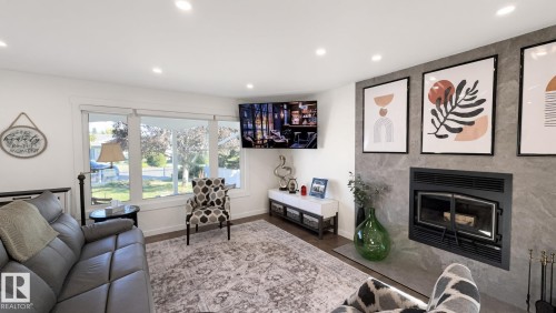 Recessed ceiling lighting, large windows, wood-finish flooring, built-in fireplace, and stone-finish fireplace surround - 3508 106A Street Nw, Edmonton, AB 