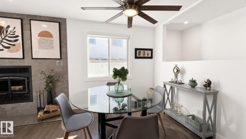 Wood-finish flooring, built-in fireplace with stone-finish surround, window with white trim, ceiling fan with integrated lighting, and recessed lighting - 3508 106A Street Nw, Edmonton, AB 
