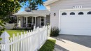 White picket fence, covered front porch, light gray exterior siding, attached garage with decorative windows, and concrete driveway - 3508 106A Street Nw, Edmonton, AB 