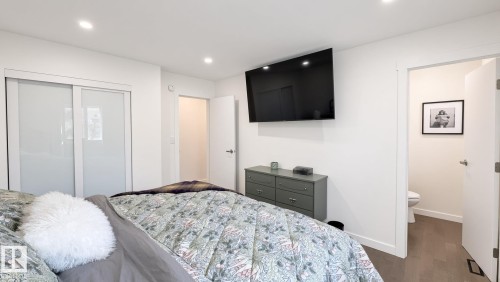 Recessed lighting, white walls, wood-finish flooring, sliding closet doors with frosted glass panels, and a wall-mounted television - 3508 106A Street Nw, Edmonton, AB 