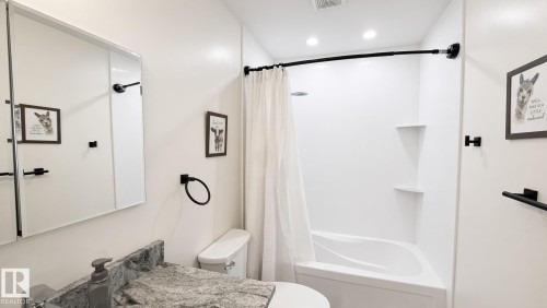 White bathtub with integrated corner shelving, complemented by a medicine cabinet with mirrored doors - 3508 106A Street Nw, Edmonton, AB 