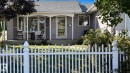 Front exterior featuring a white picket fence, covered front porch, bay window with shutters, and gray horizontal siding - 3508 106A Street Nw, Edmonton, AB 