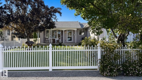 Exterior featuring a white picket fence, mature trees, and a covered porch entry - 3508 106A Street Nw, Edmonton, AB 