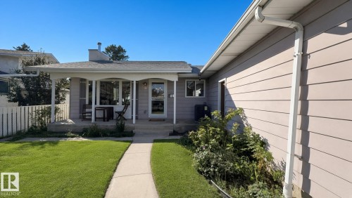 Covered front porch with white columns, light-colored siding, and a manicured lawn - 3508 106A Street Nw, Edmonton, AB 