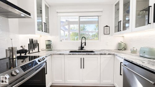 White shaker cabinetry, stone countertops, stainless steel appliances, black sink, and matte black fixtures - 3508 106A Street Nw, Edmonton, AB 