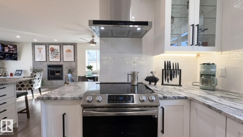 Stainless steel range with a built-in hood, white shaker-style cabinetry, and stone countertops - 3508 106A Street Nw, Edmonton, AB 