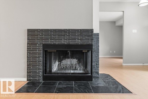 Fireplace featuring a dark tile surround and hearth - #4 14620 26 St Nw, Edmonton, AB 
