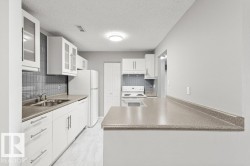 Kitchen featuring light cabinetry, tile flooring, and a stone-finish countertop - 