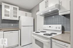 Contemporary kitchen featuring white cabinetry, a full-size refrigerator, an electric range with overhead exhaust hood, a dishwasher, and a tiled backsplash - 