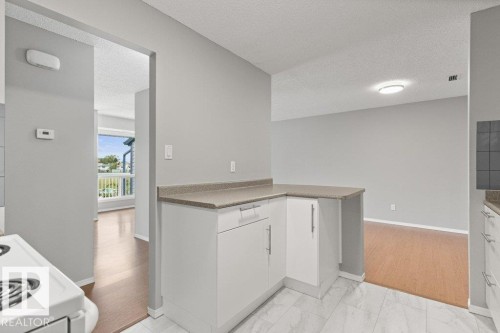 White kitchen cabinetry with brushed nickel hardware, laminate countertops, and white tile flooring - #4 14620 26 St Nw, Edmonton, AB 