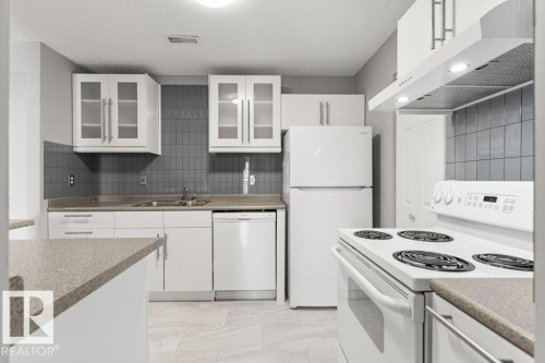 White appliances and cabinetry, grey tile backsplash, and light-toned countertop - #4 14620 26 St Nw, Edmonton, AB 