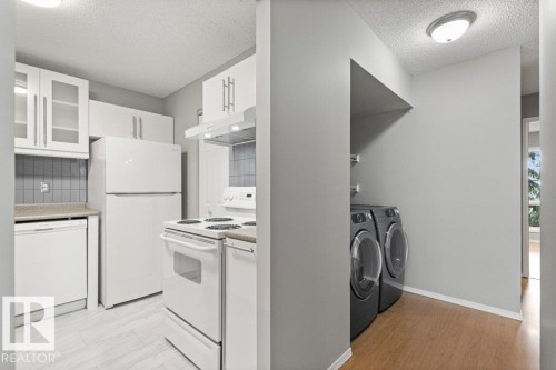 Kitchen featuring white cabinetry, gray tile backsplash, and light-toned wood-finish flooring - #4 14620 26 St Nw, Edmonton, AB 